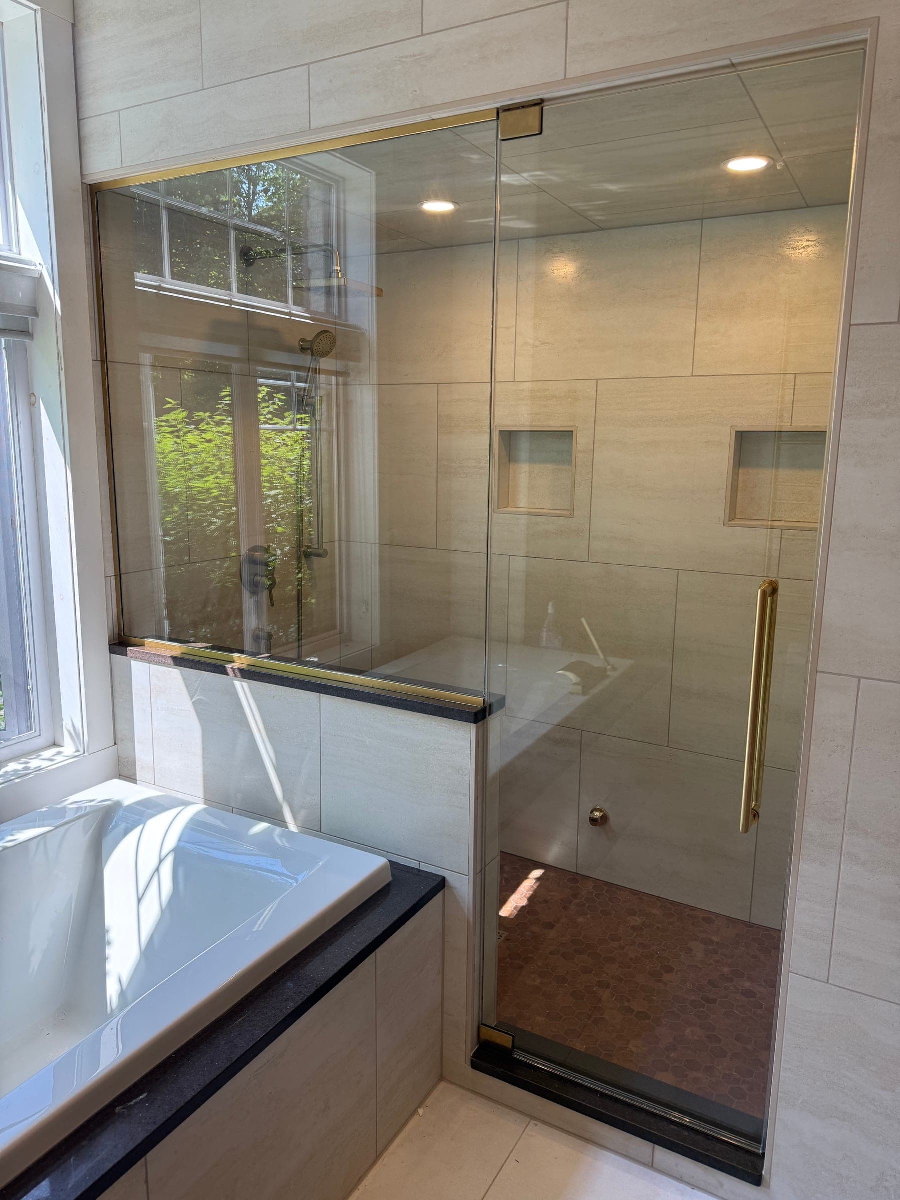 Cabine de douche en verre à quincaillerie laiton doré, sur pierre claire