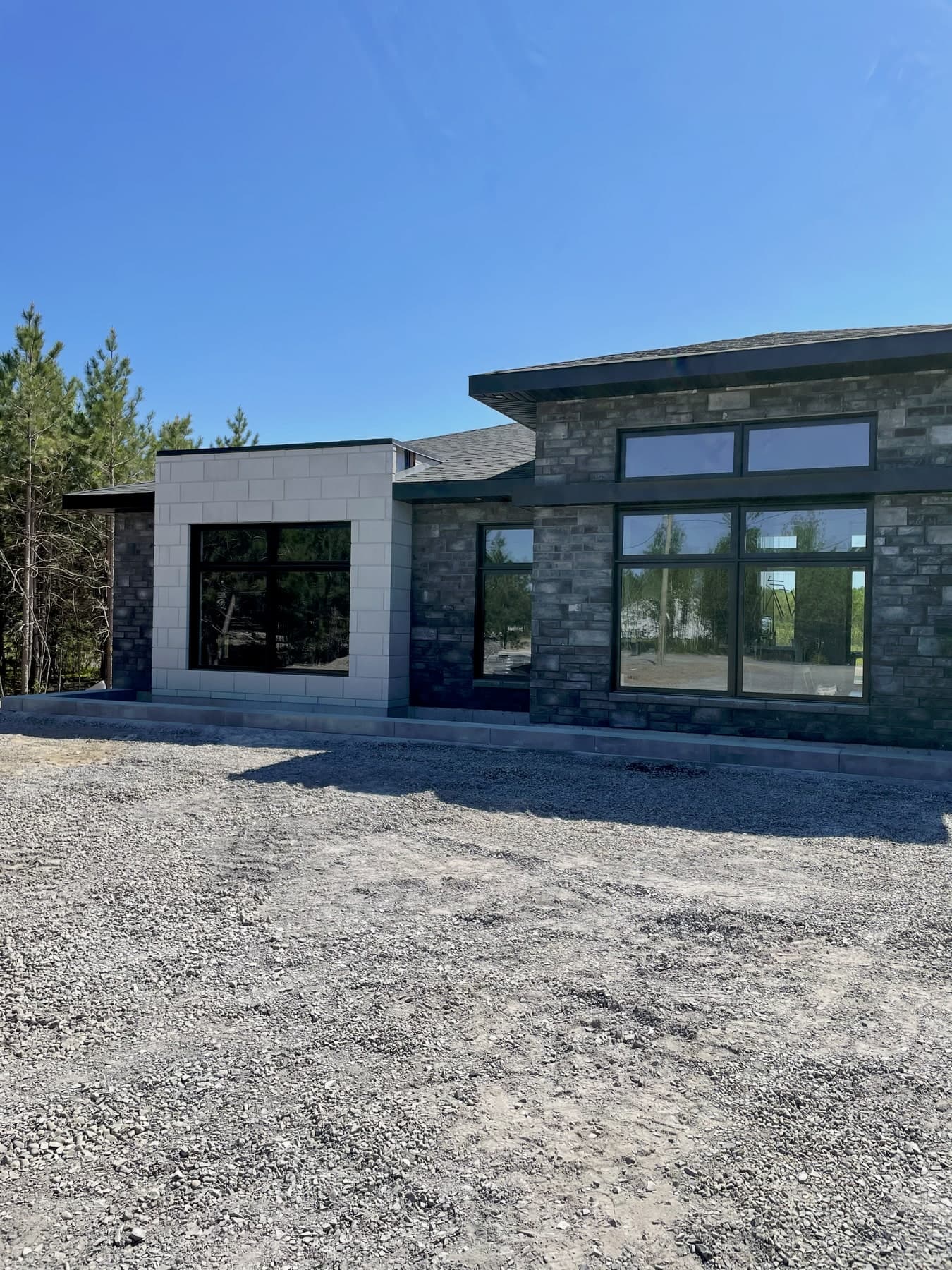 Grandes fenêtres à cadres noirs sur une maison contemporaine en pierre